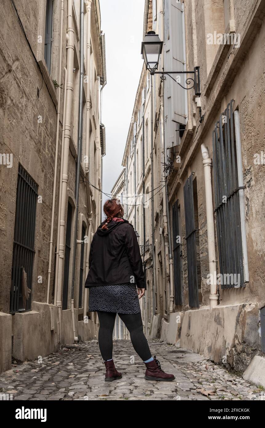 Woman with red hair on a traditional narrow street in a an old European town - Montpellier, southern France Stock Photo