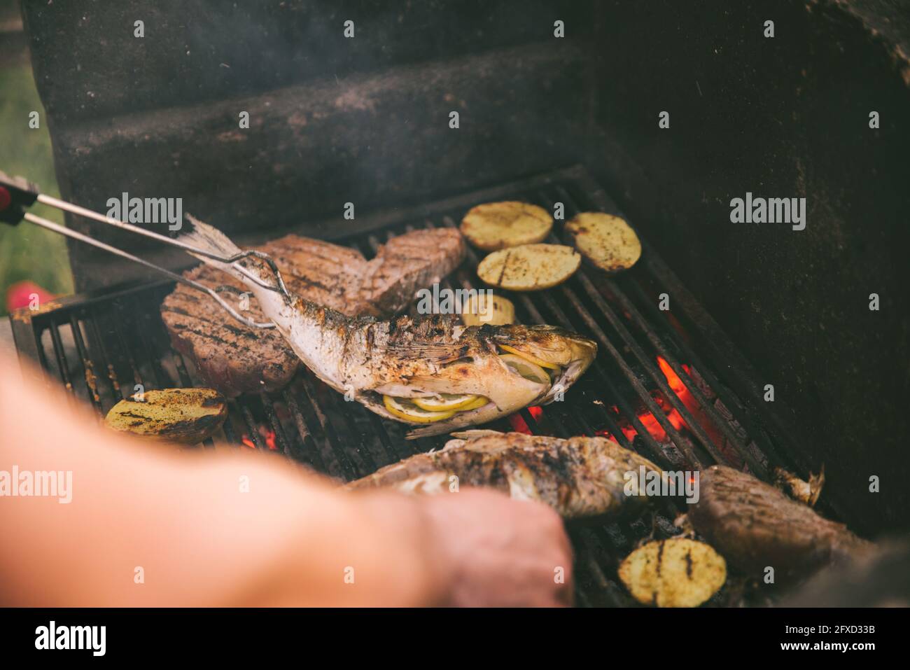 cooking fish and potatoes on grill outdoors Stock Photo - Alamy