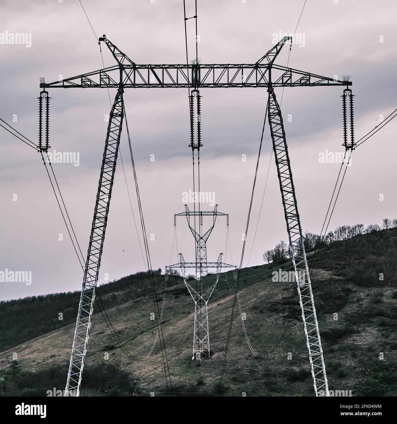 Transmission towers on hills under a cloudy sky in the evening Stock ...
