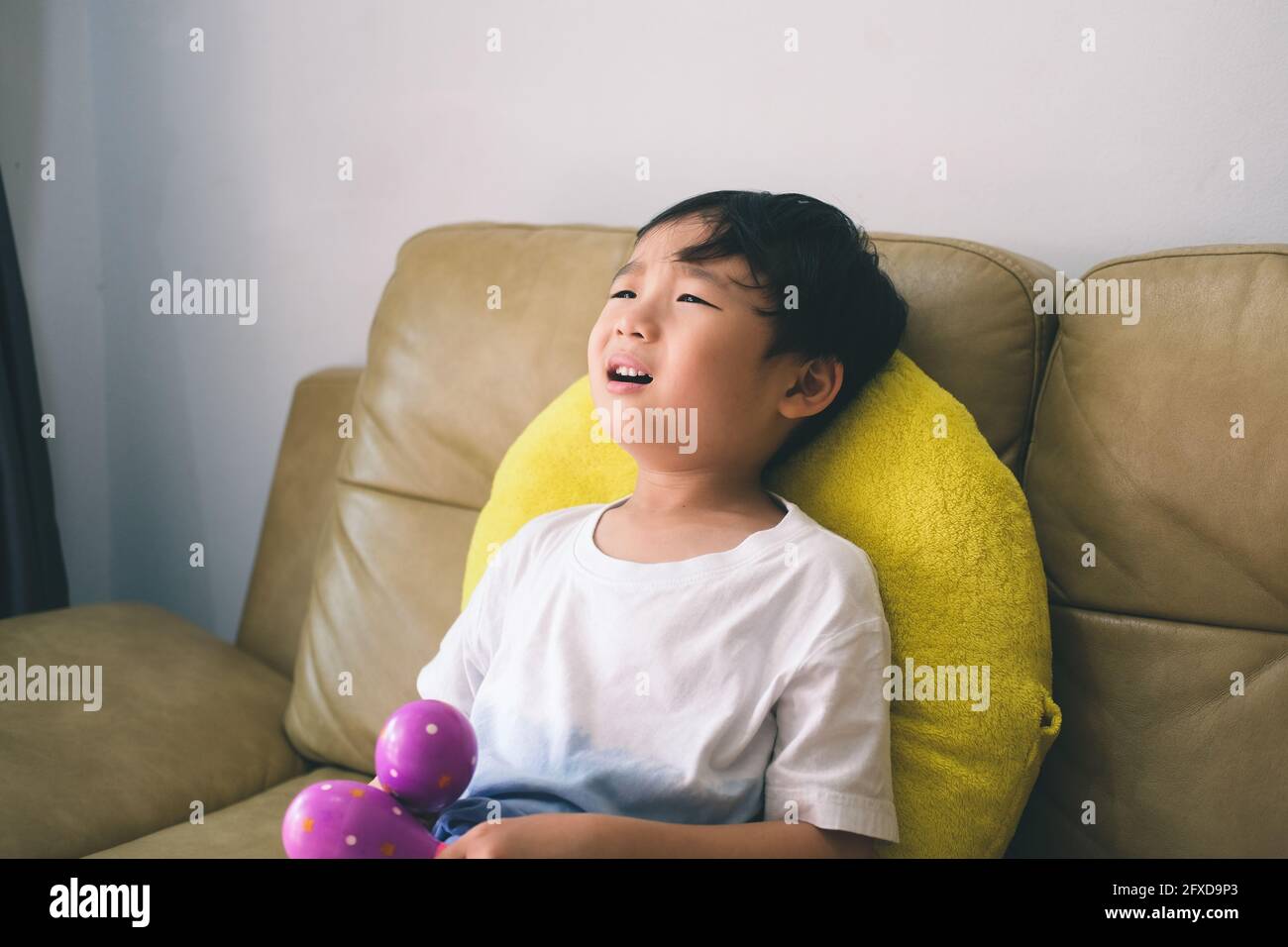 Frustrated little boy siting on sofa at home Stock Photo