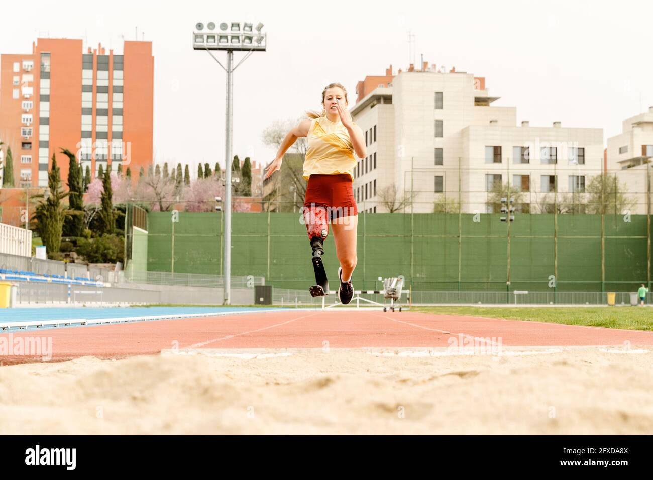 Female athlete with disability running towards sandpit Stock Photo