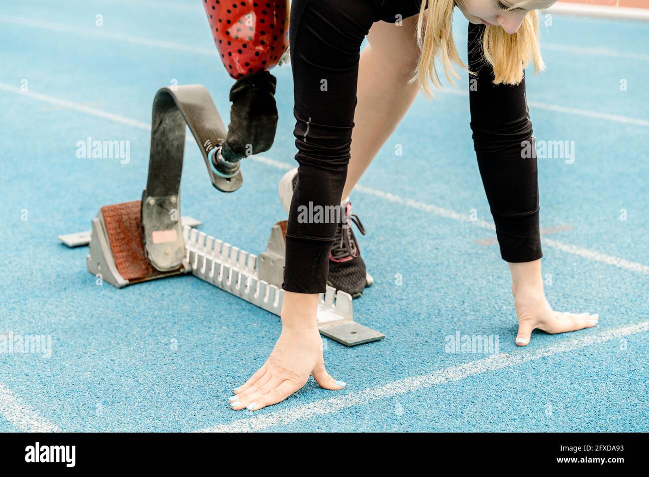 Crop sportswoman with disability standing in crouch start position