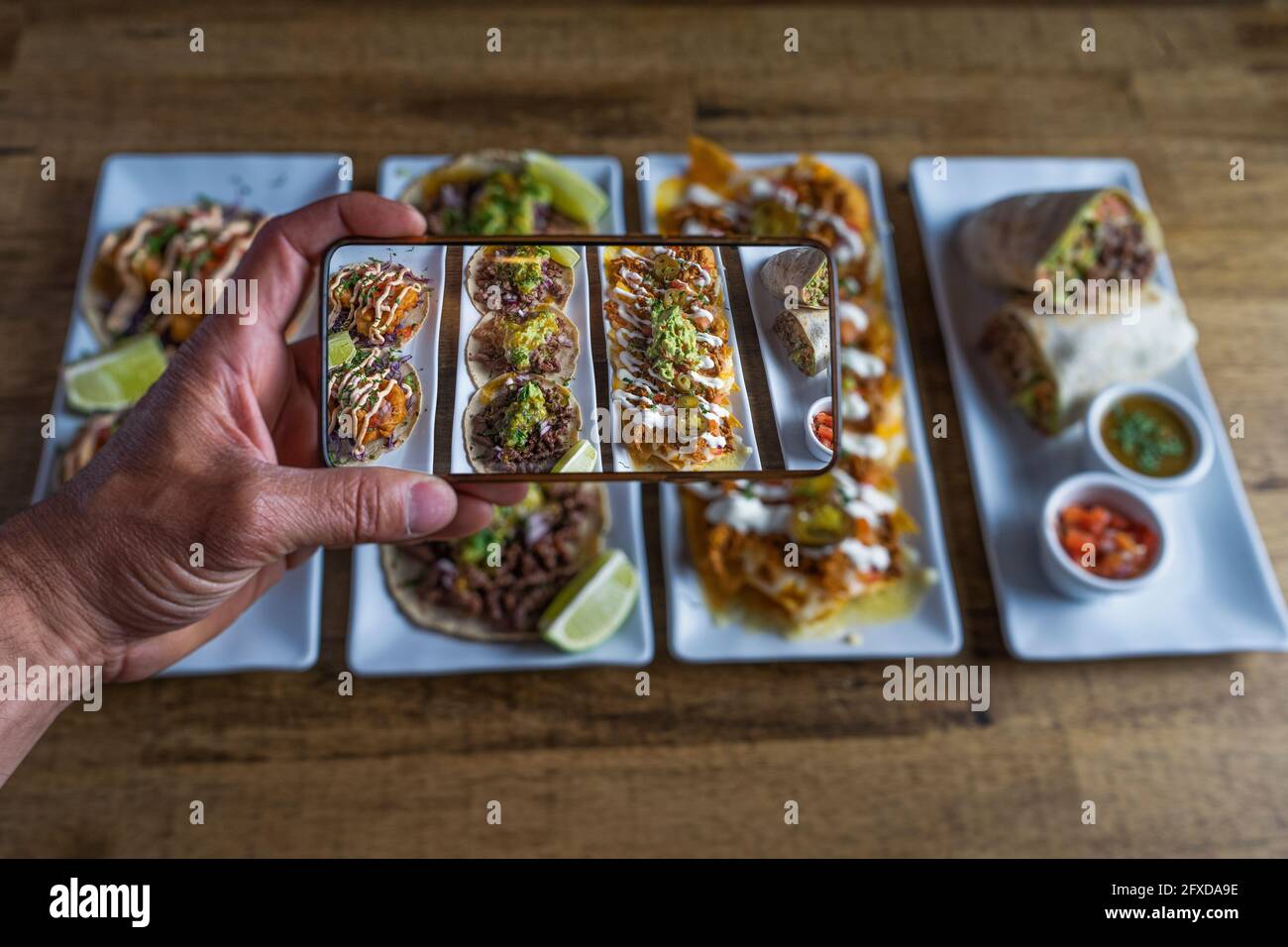 Man takes a photo of Mexican food dishes on the restaurant table Stock Photo