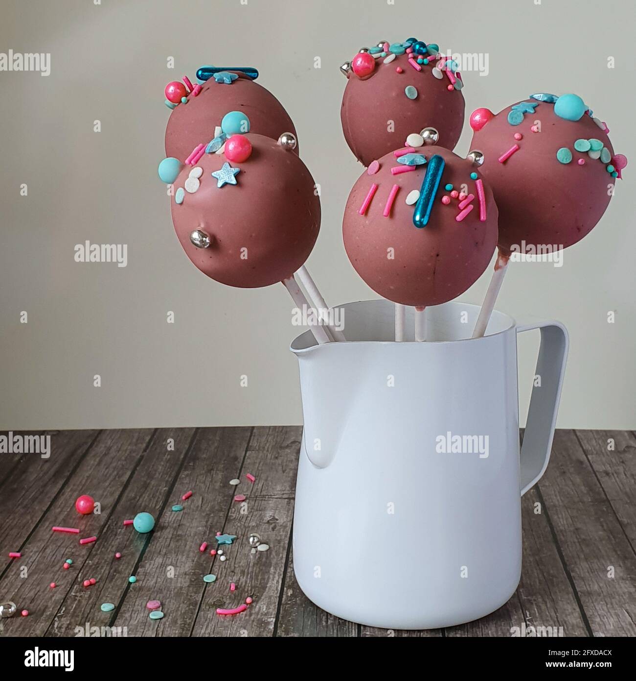Fine pink chocolate cake pops with bright multicolor sprinkes in a jar Stock Photo