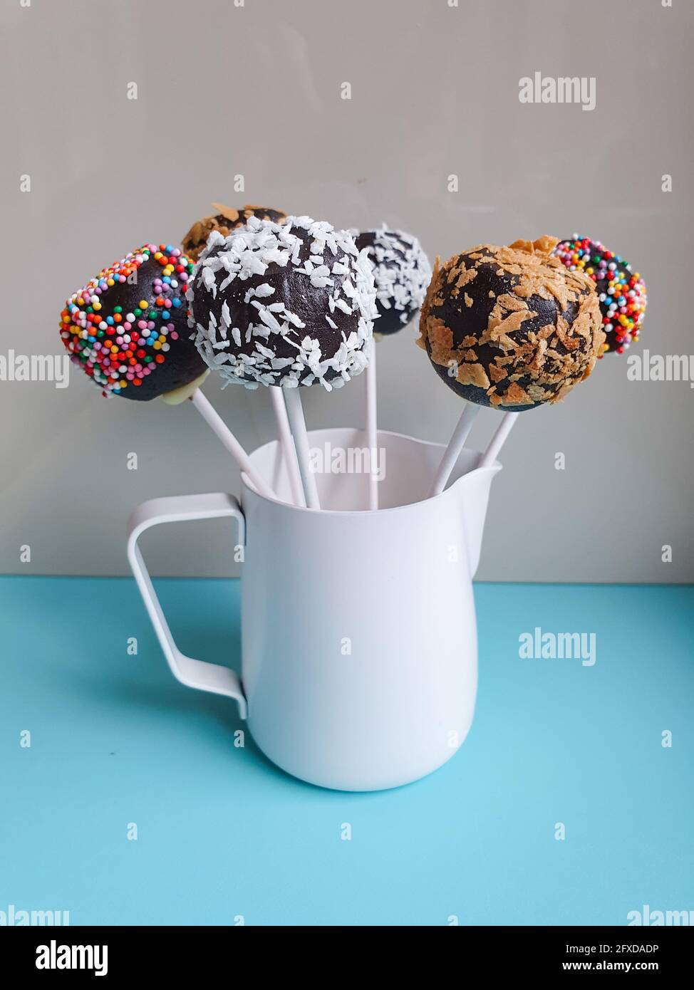 Six decorated cake pops standing in white pitcher Stock Photo