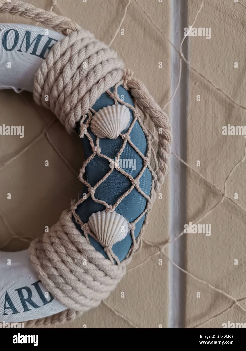 Vertical shot of a lifeguard circle with decorative rope on a beige ...