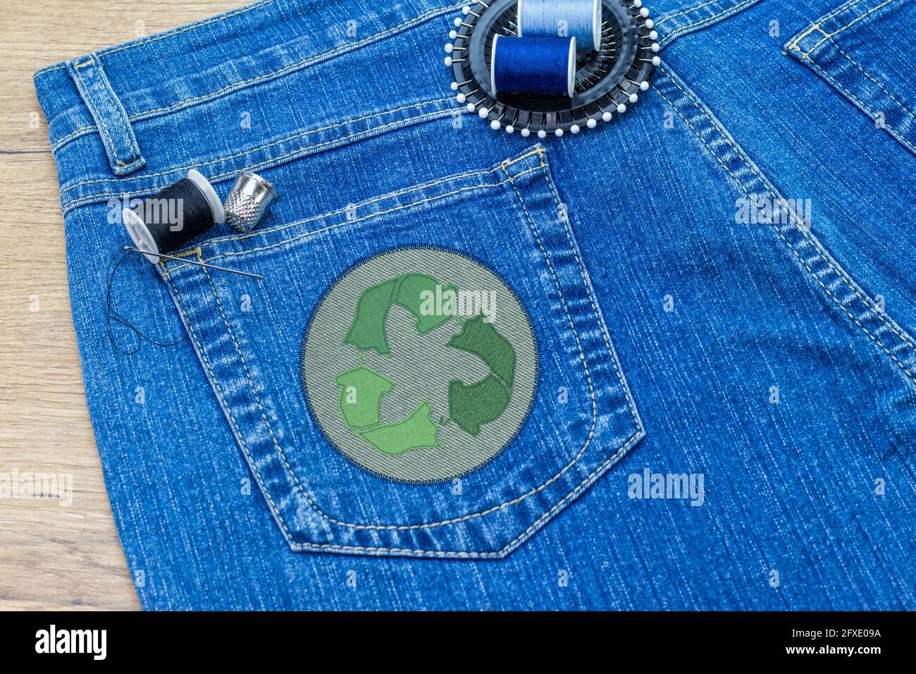 Recycle clothes icon patch on jeans, sustainable fashion visible mending concept, repair, recycle, reuse clothes and textiles to reduce waste Stock Photo