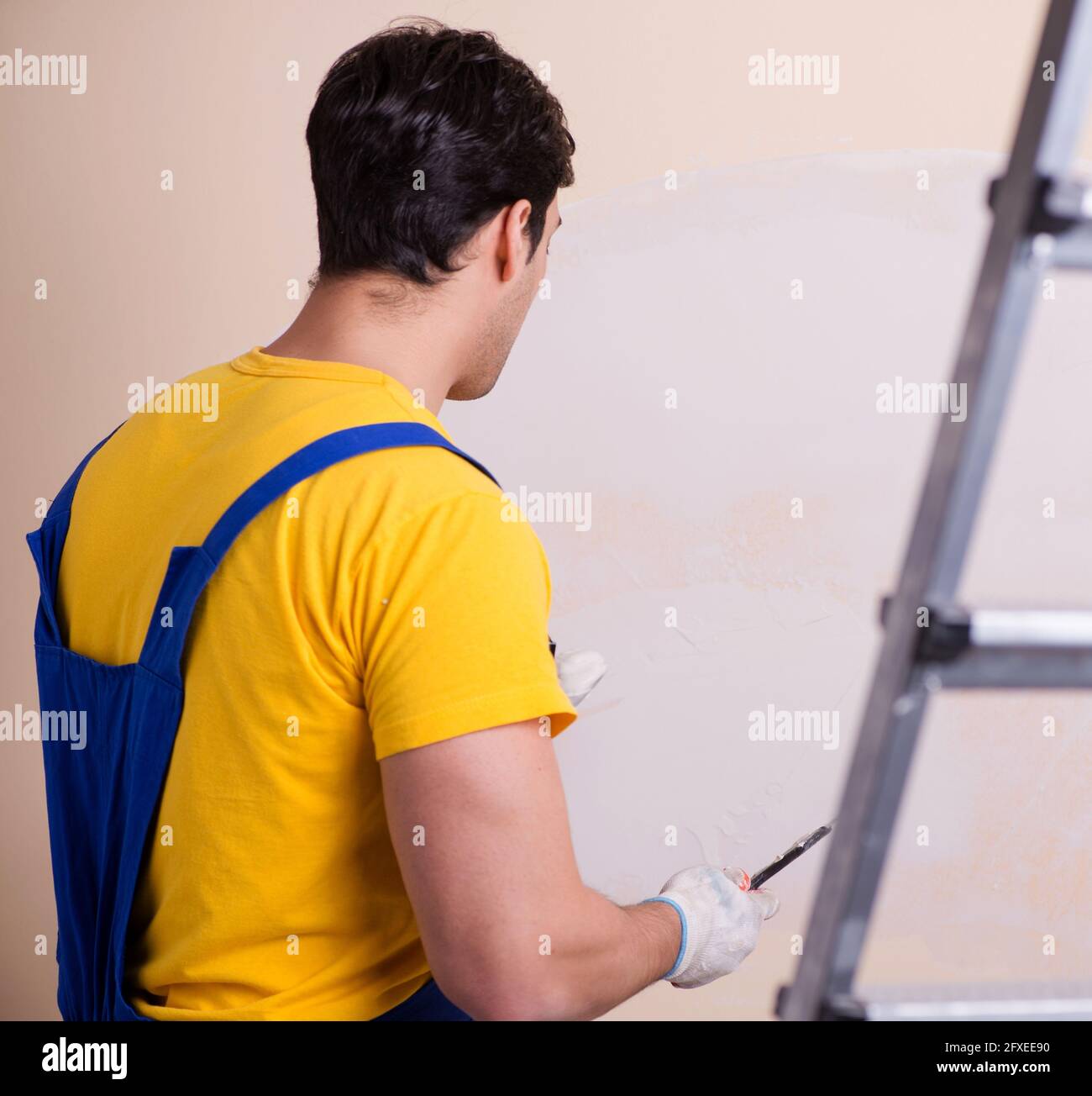 The young contractor employee applying plaster on wall Stock Photo