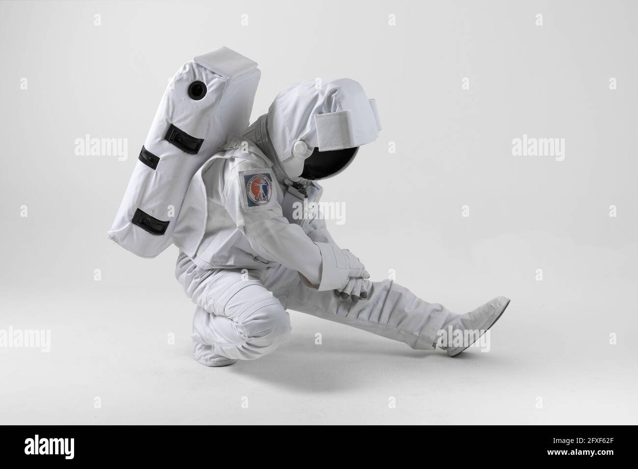 Astronaut stretching before exercise, white background Stock Photo