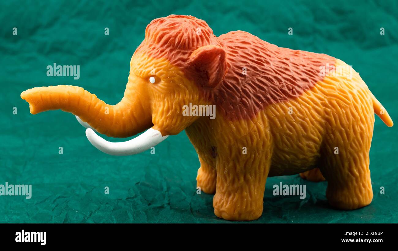 Little toy mammoth on green background Stock Photo