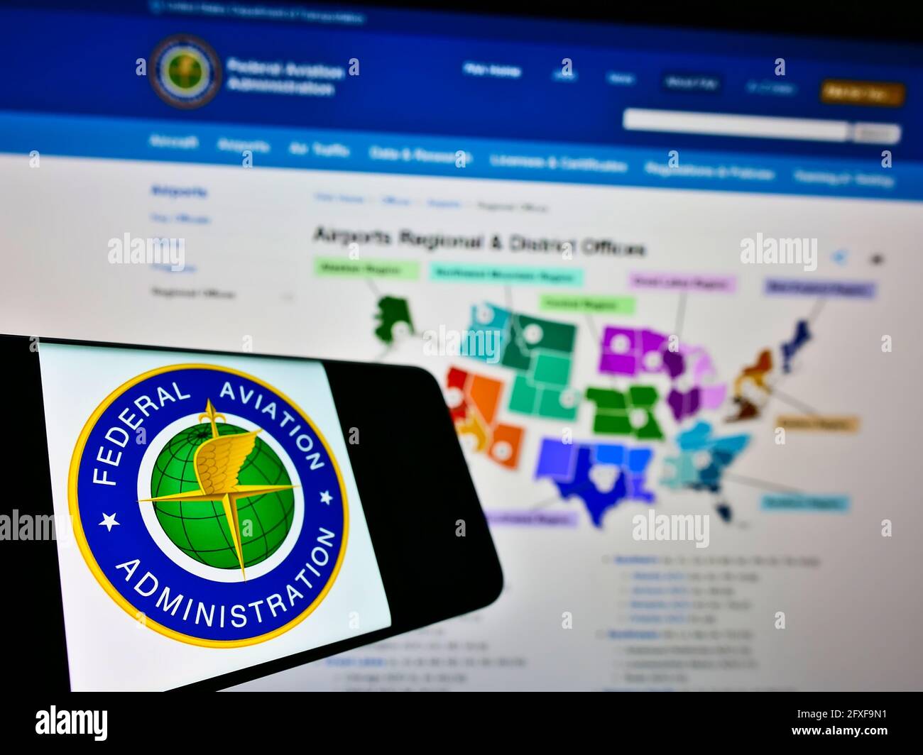 Smartphone with seal of American agency Federal Aviation Administration (FAA) on screen in front of website. Focus on center-left of phone display. Stock Photo