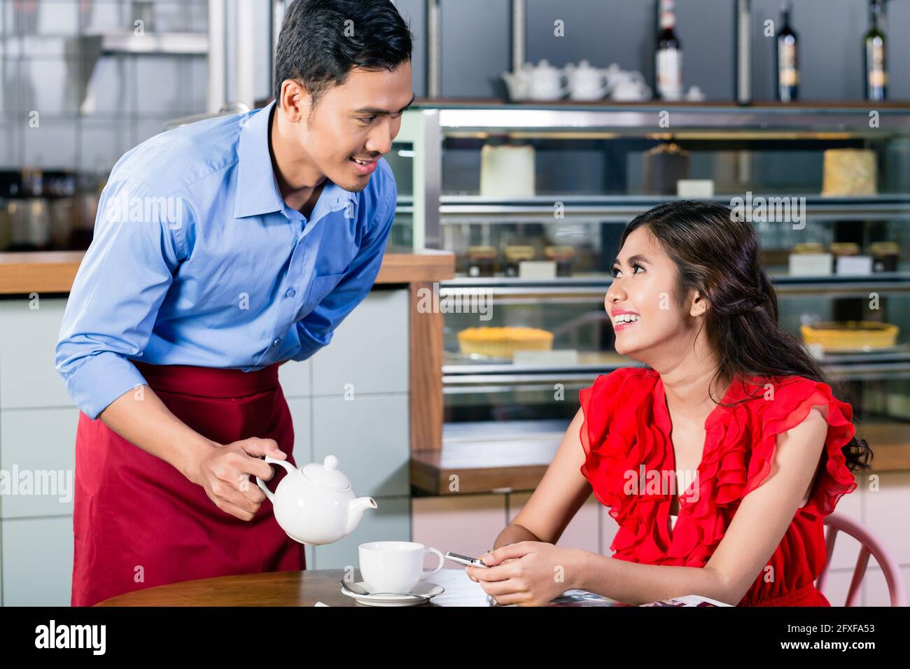 Handsome waiter flirting with a beautiful young woman while serving