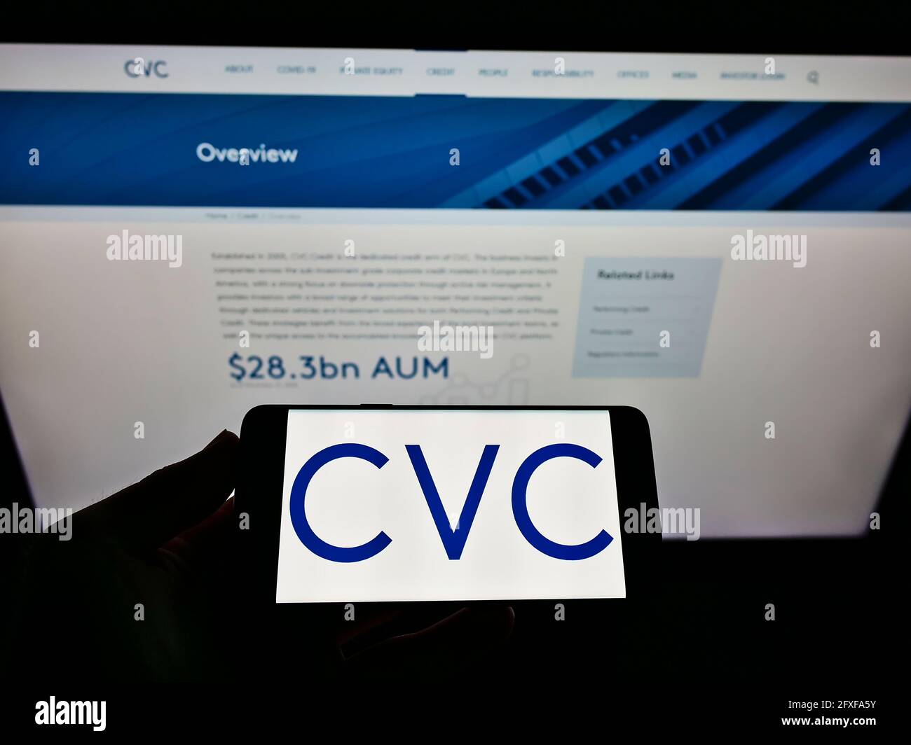 Person holding smartphone with business logo of private equity company CVC Capital Partners on screen in front of website. Focus on phone display. Stock Photo