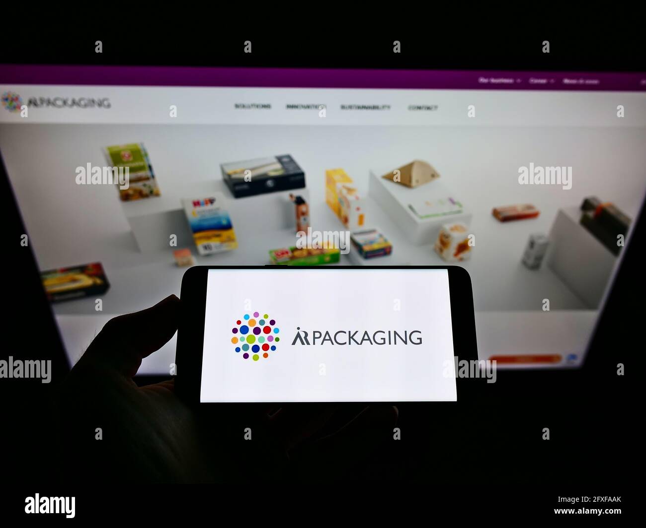 Person holding smartphone with logo of Swedish company ÅR Packaging Group AB on screen in front of website. Focus on phone display. Stock Photo
