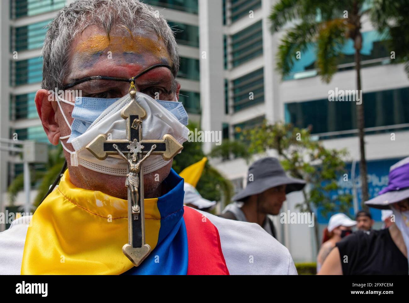 Medellin, Colombia. 26th May, 2021. A demonstrator with its face painted with the Colombian national flag carries a crucifix and a Colombian flag wrapped on its neck in a performing arts demonstration as artists and demonstrators protested against the government of president Ivan Duque Marquez and the abuse of force by police that leads to at least 40 dead across the country since the nation wide antigovernment protests started. In Medellin, Colombia on May 26, 2021. Credit: Long Visual Press/Alamy Live News Stock Photo