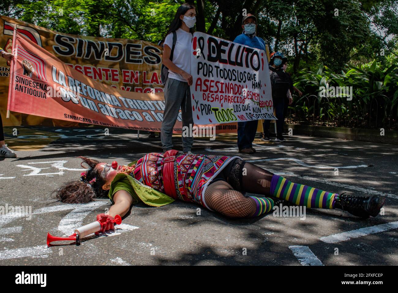Medellin, Colombia. 26th May, 2021. A demostrator wearing a clown costume, nose and makeup lies on the ground performing as its being shot in a performing arts demonstration as artists and demonstrators protested against the government of president Ivan Duque Marquez and the abuse of force by police that leads to at least 40 dead across the country since the nation wide antigovernment protests started. In Medellin, Colombia on May 26, 2021. Credit: Long Visual Press/Alamy Live News Stock Photo
