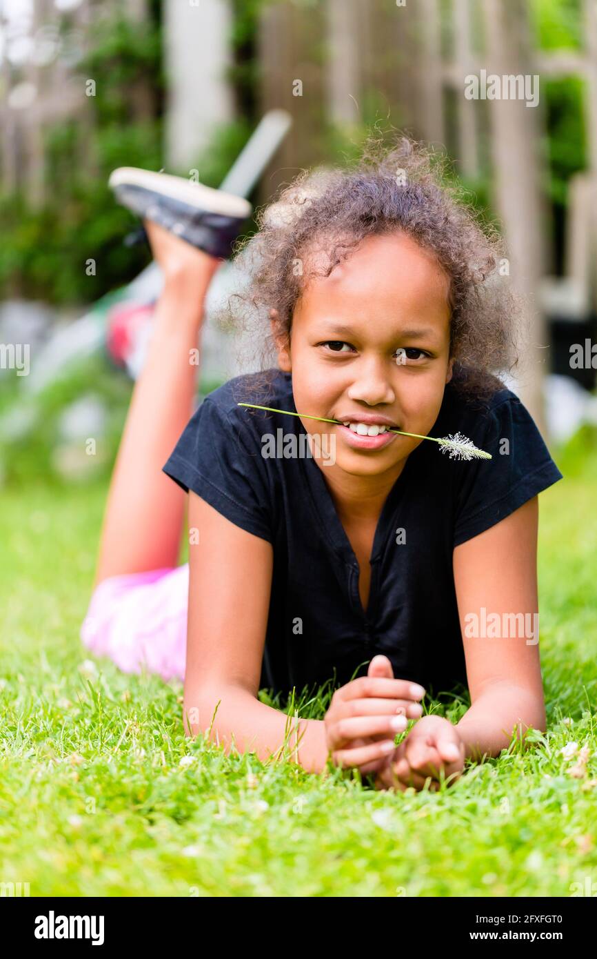 Black girl lying with grass blade on meadow Stock Photo - Alamy