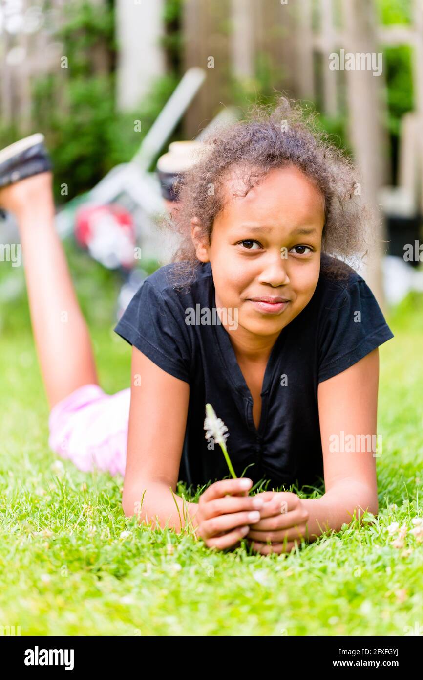 Black girl lying with grass blade on meadow in summer Stock Photo - Alamy