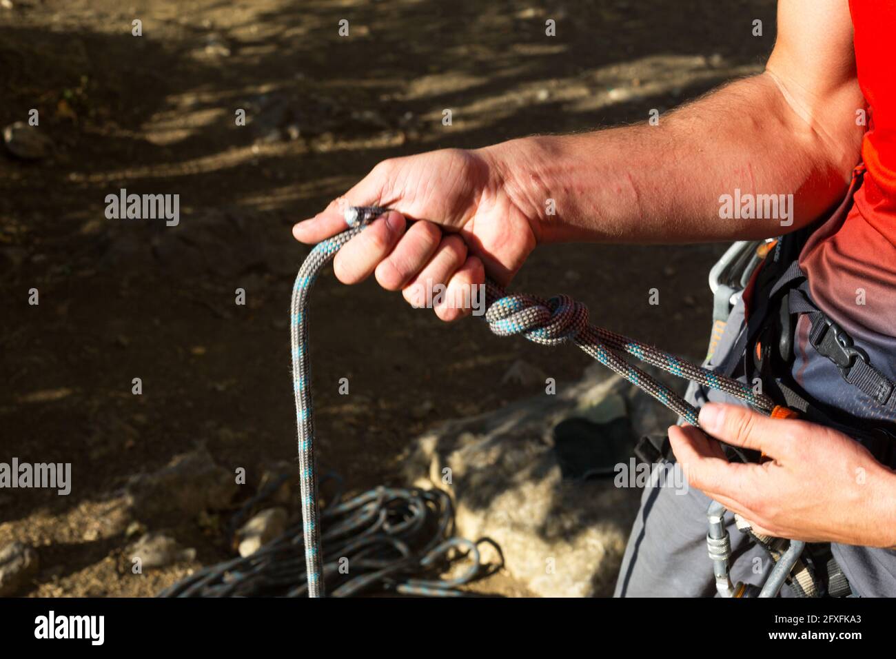 A male climber ties a safety knot eight on the harness before climbing