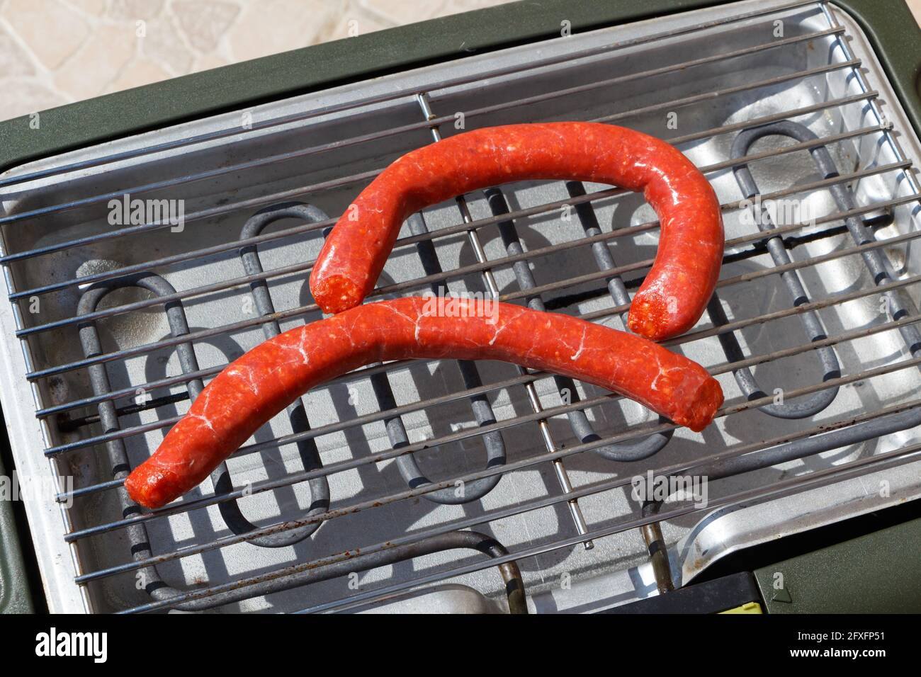 Two raw merguez on the grid of an electric barbecue Stock Photo