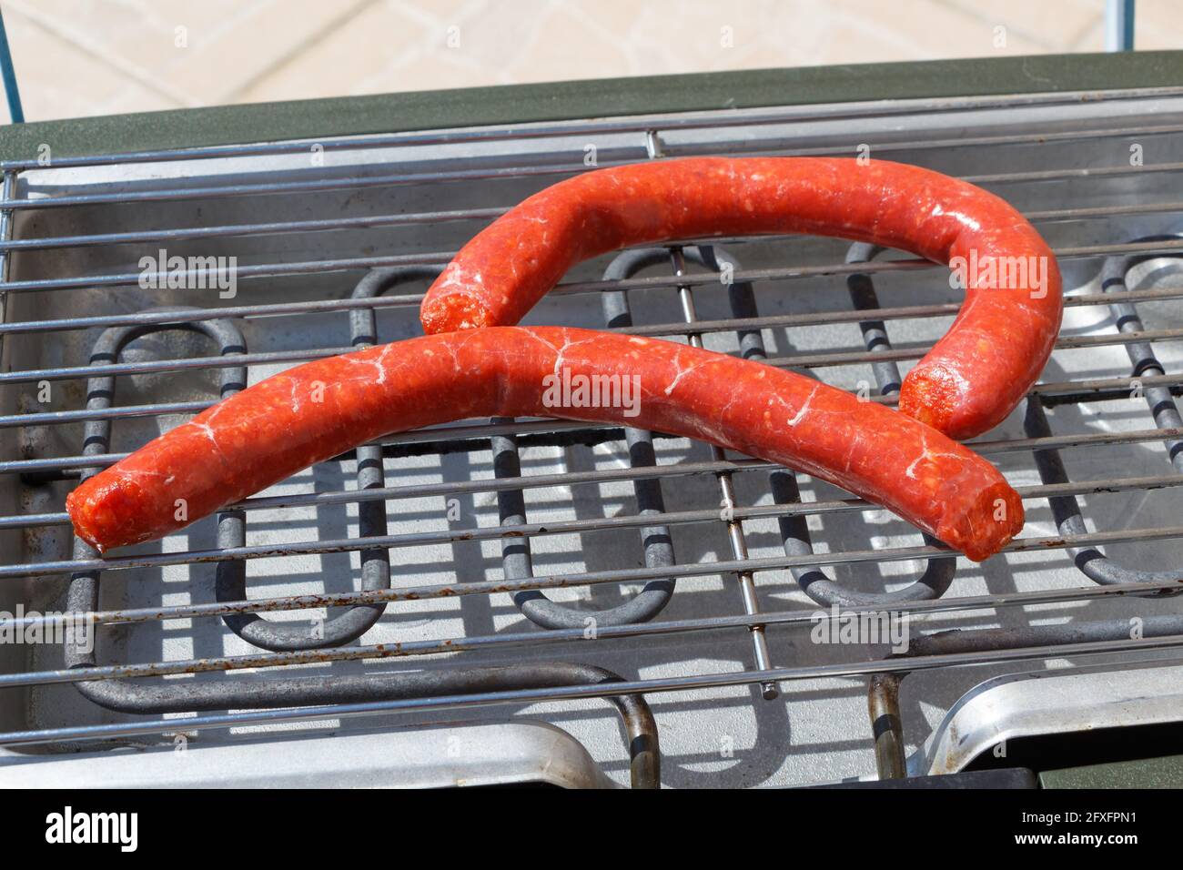 Two raw merguez on the grid of an electric barbecue Stock Photo