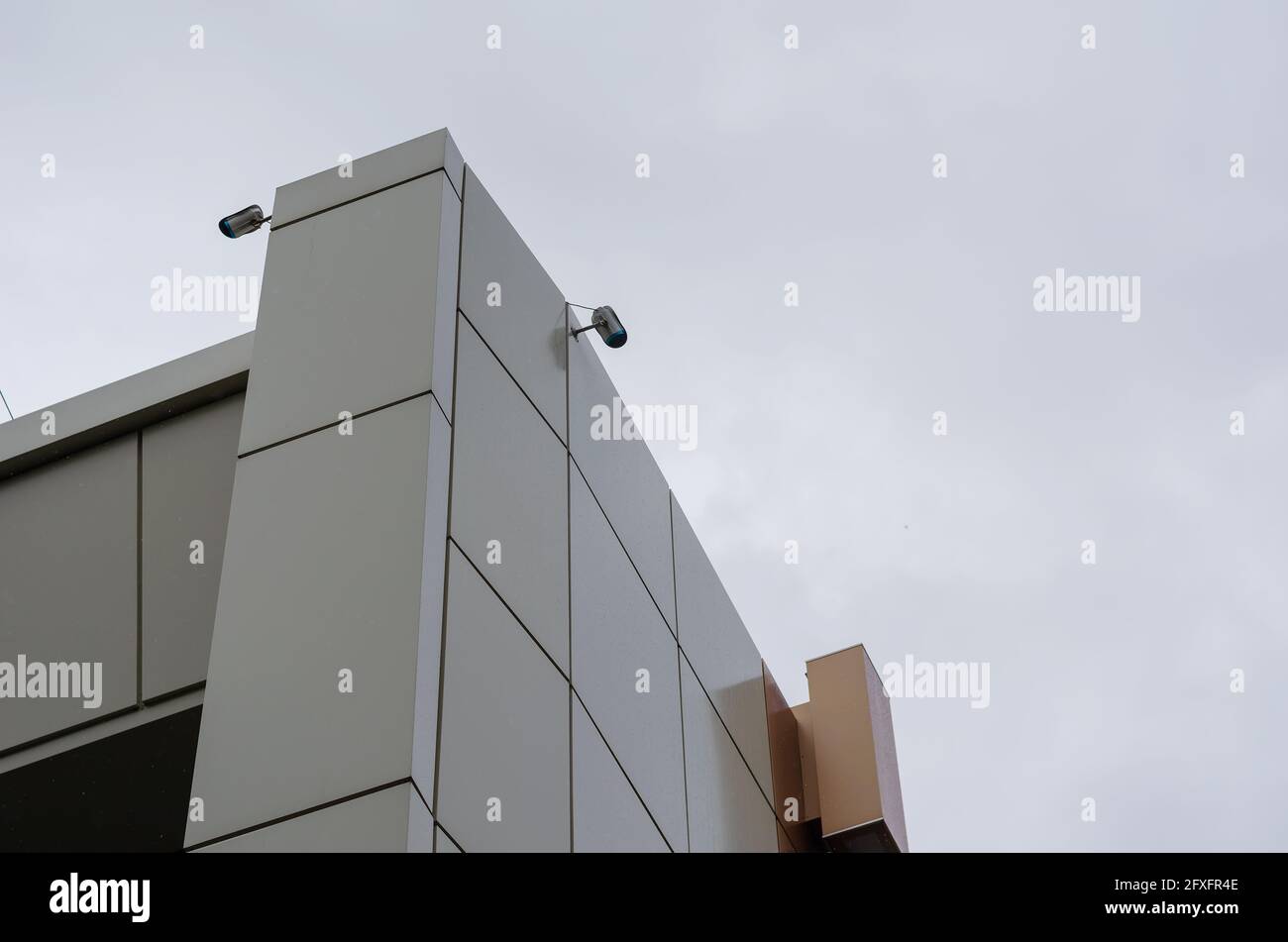 Video surveillance system on the corner of the Beige and Brown building. Two video cameras against an overcast sky. Daytime. Shooting in the rain. Arc Stock Photo