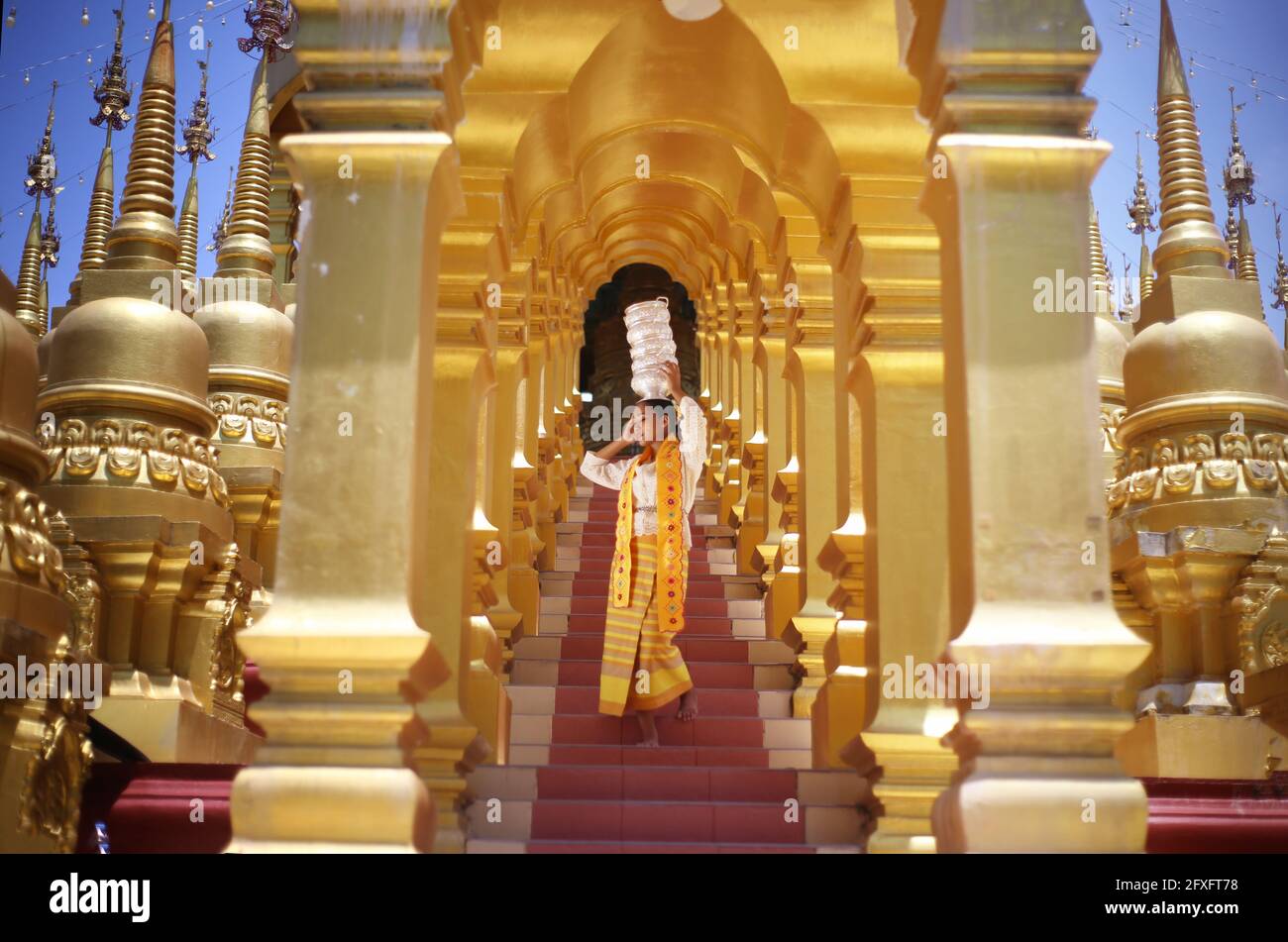 Young girl with traditional Burmese holding bowl of rice on the hand at beautiful golden pagoda in Myanmar Stock Photo