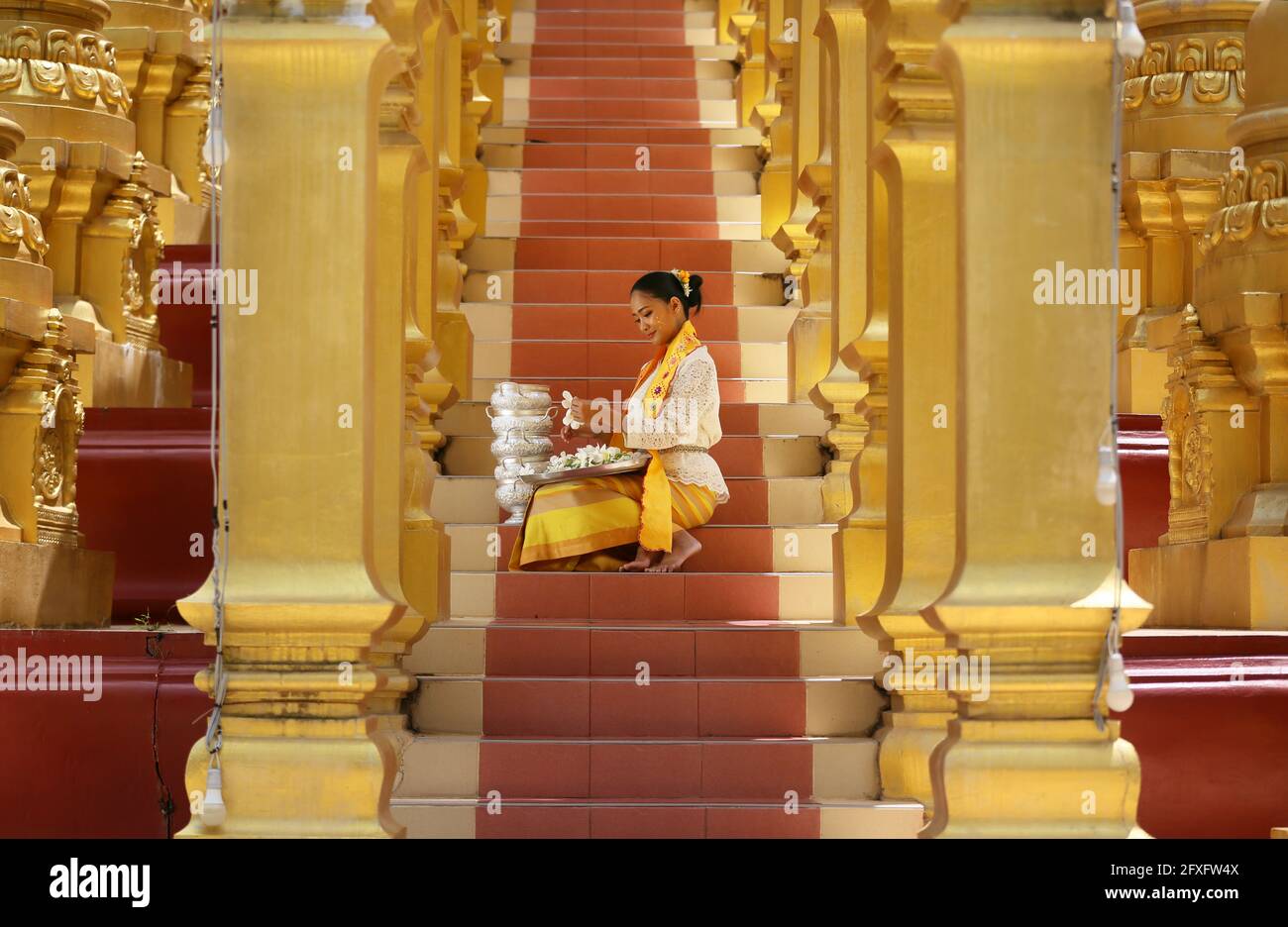 Myanmar women holding flowers at a temple. Southeast Asian young girls with burmese traditional dress visiting a Buddihist temple Stock Photo