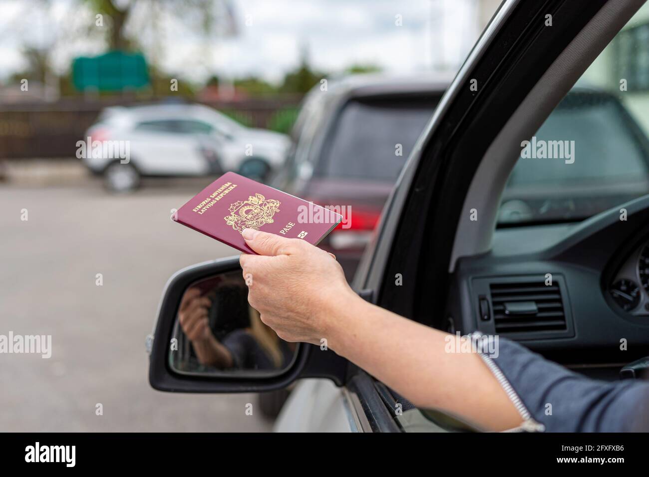 women hand through car window giving passport for customs control, driver with an identity card in a car at a border checkpoint Stock Photo