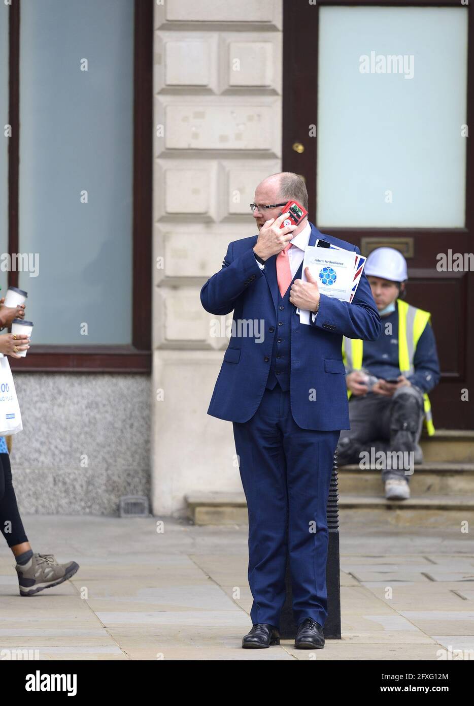 George Freeman MP (Con: Mid Norfolk) on his mobile phone in Whitehall, 26th May 2021, holding the paper 'Reform for Resilience' by The Post-Pandemic P Stock Photo