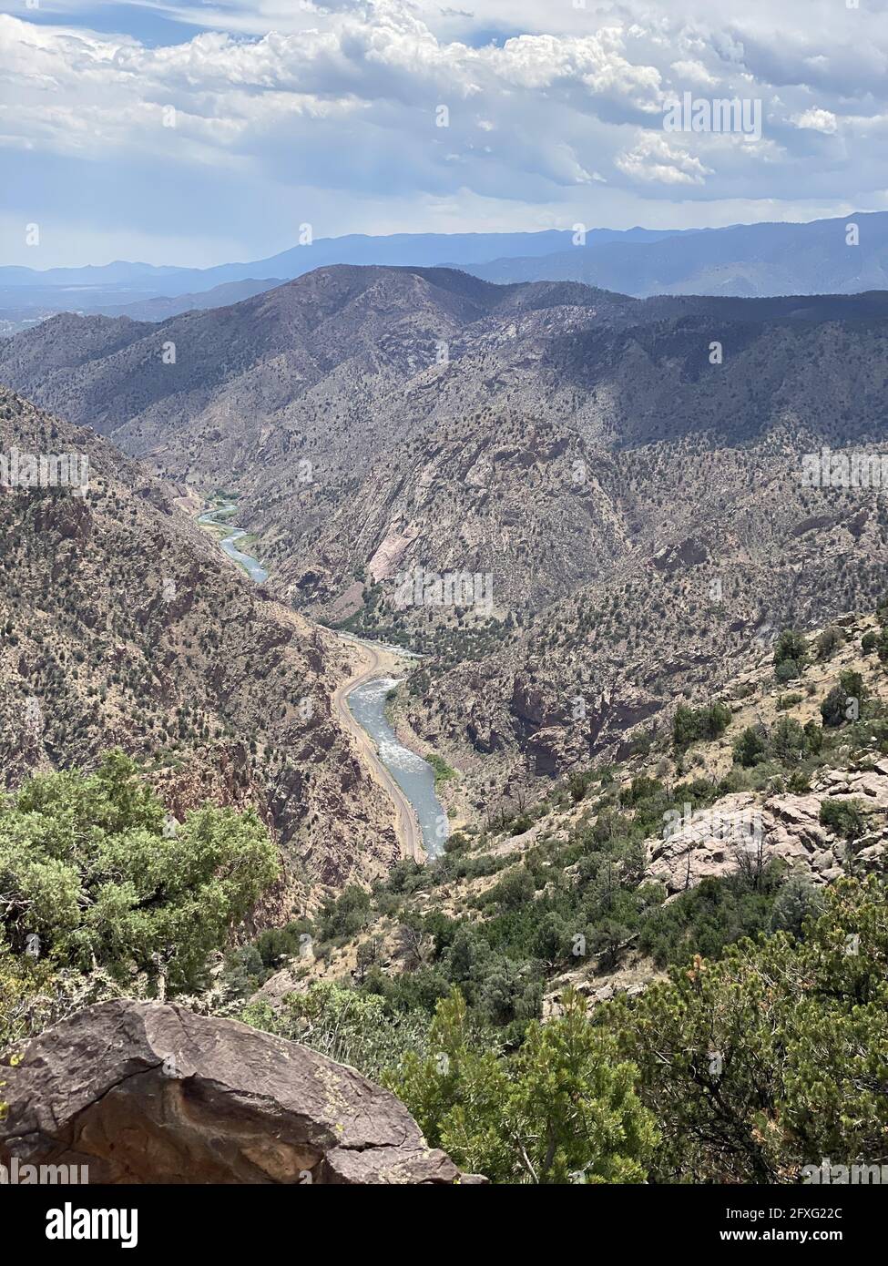 Vertical shot of a river flowing between lush hills under a cloudy sky ...