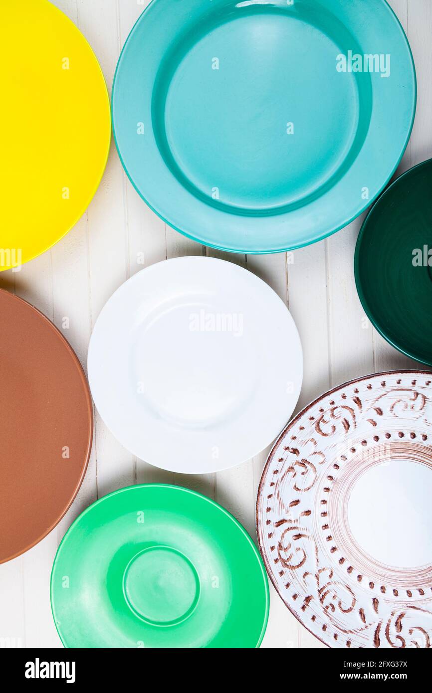 Empty multicolored plates on a wooden background, top view. Stock Photo