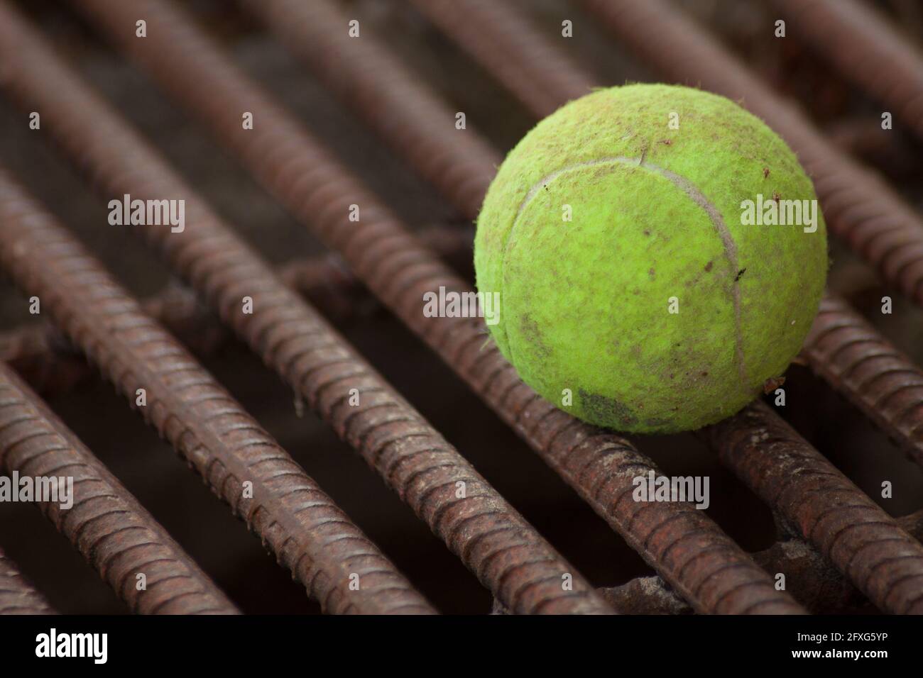 Yellow tennis ball on red iron bars Stock Photo