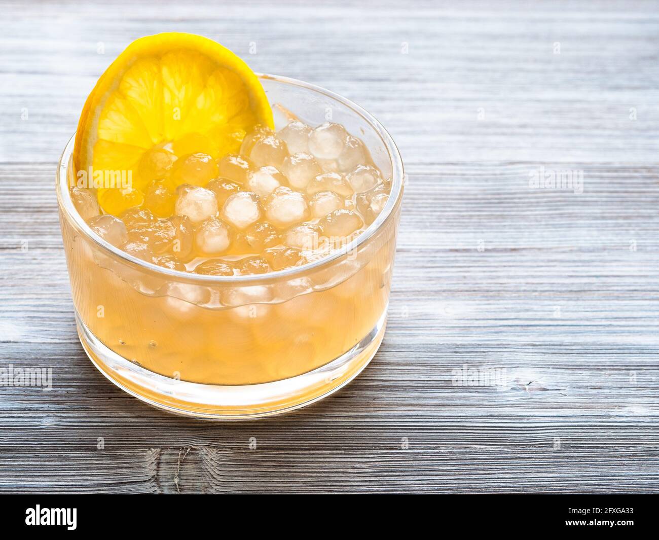 boiled boba bubbles with lemon slice in glass bowl on gray wooden table