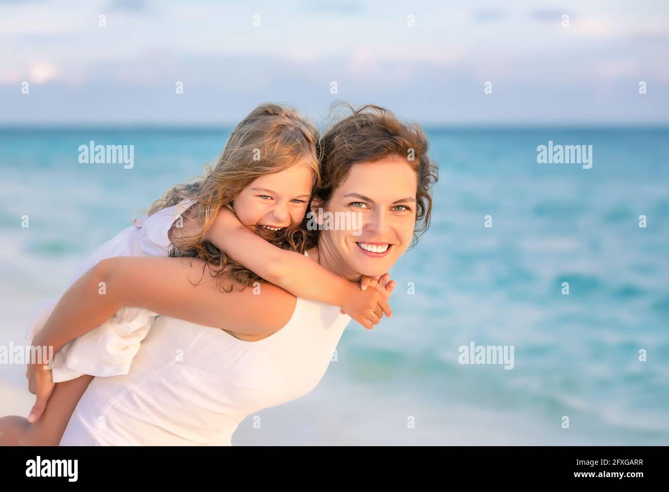 Portrait of happy mother and little daughter on ocean beach on Maldives at summer vacation. Family on the beach concept. Stock Photo