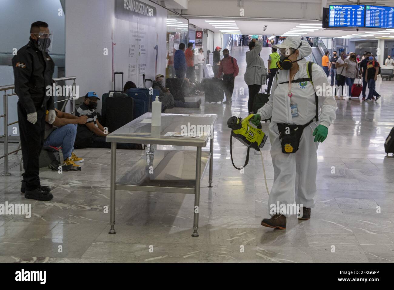 A workers wears protective suit to sprays disinfectant at Mexico City