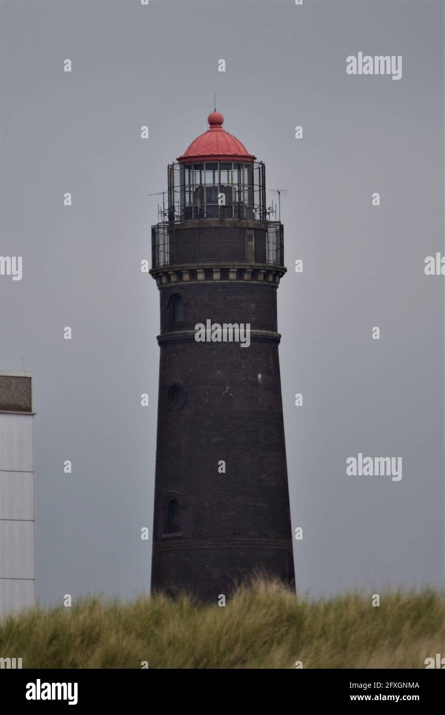 A brick lighthouse against a gray sky Stock Photo
