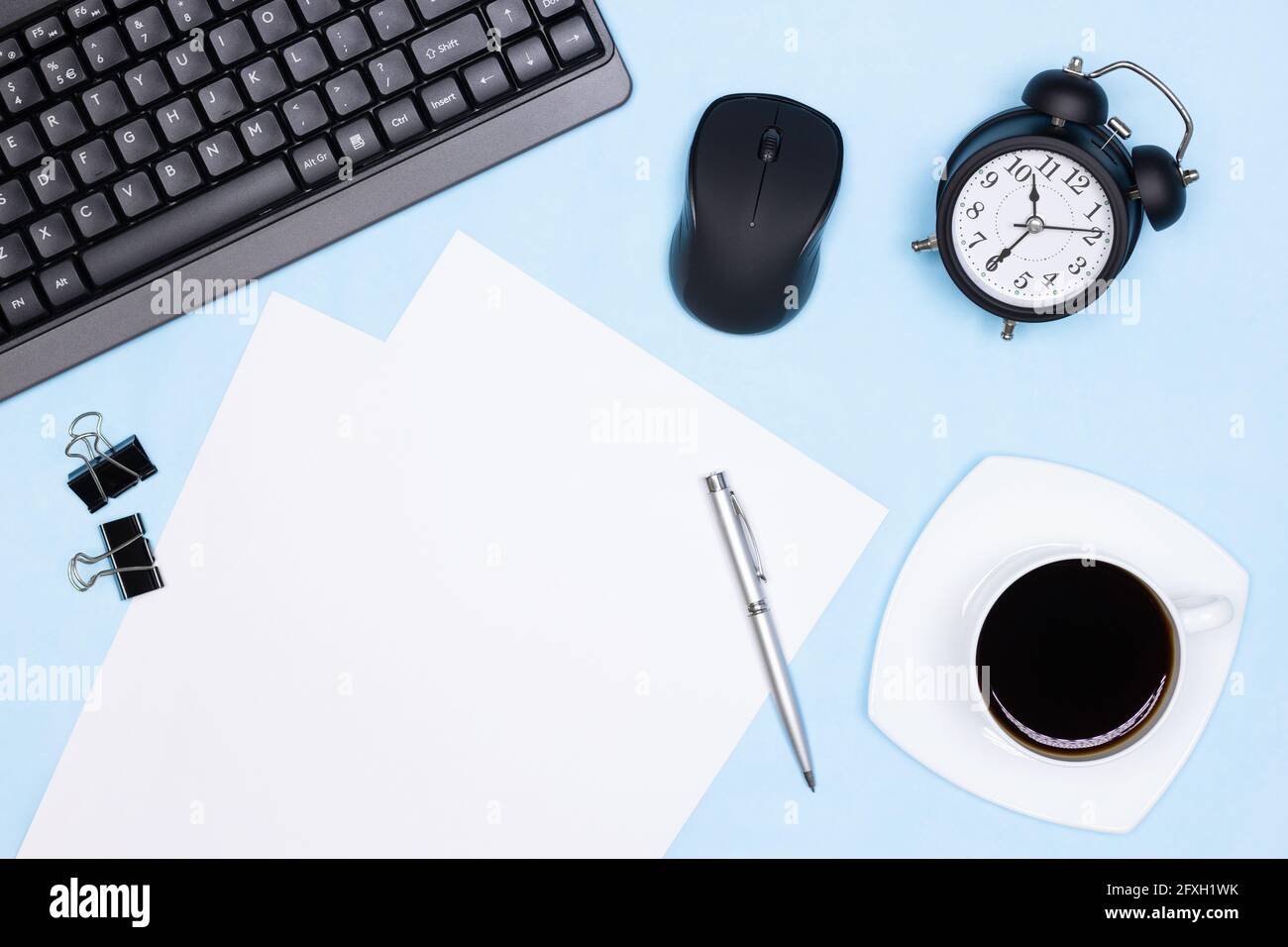 Urgent work, deadline concept. Keyboard with computer mouse, alarm clock, blank paper sheets, stationery, coffee cup on office desk Stock Photo