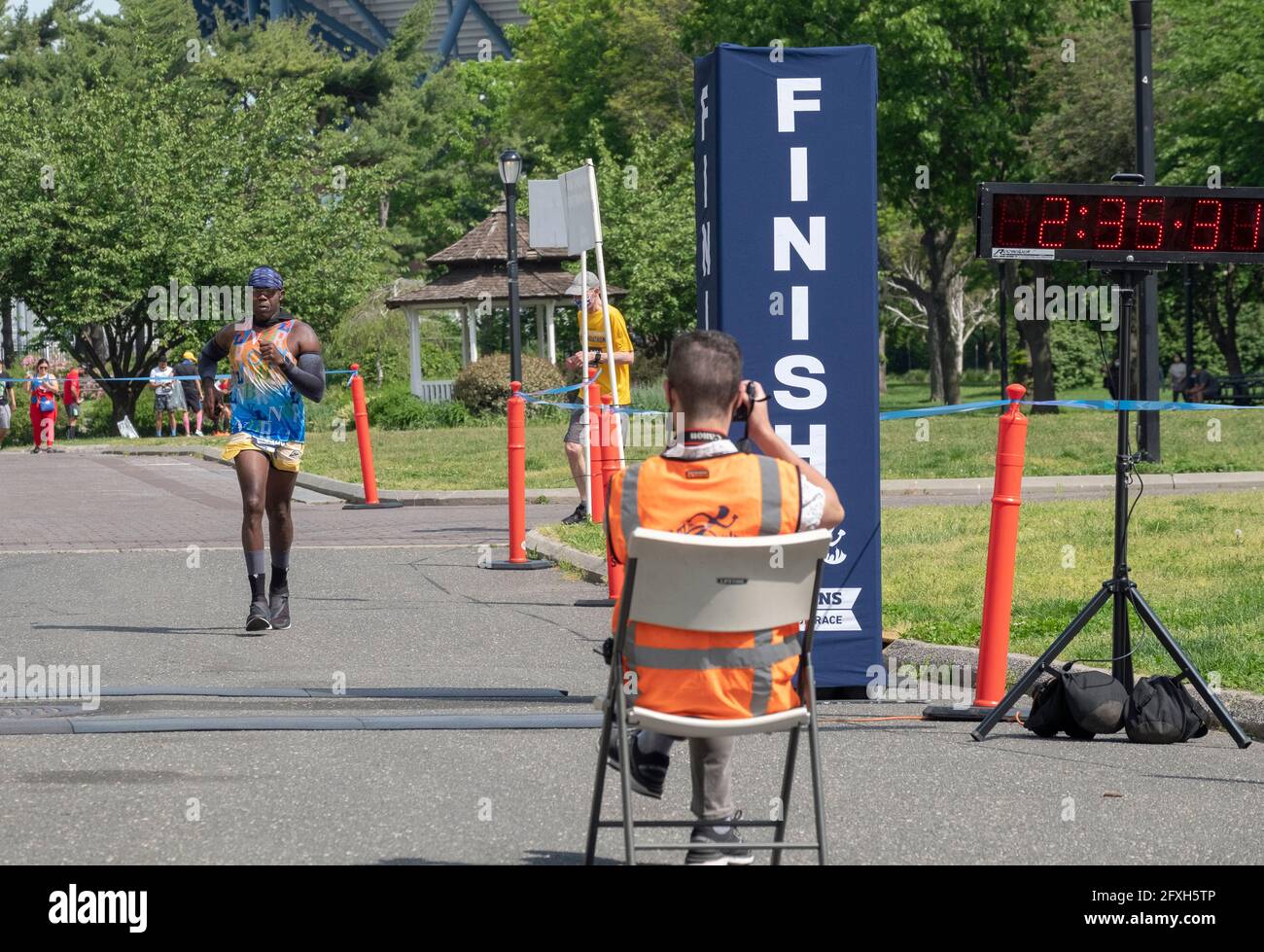 The official race photographer takes a snap of a male finisher approaching the end of the NYCRuns Queens half marathon in Flushing Meadows Corona.Th Stock Photo