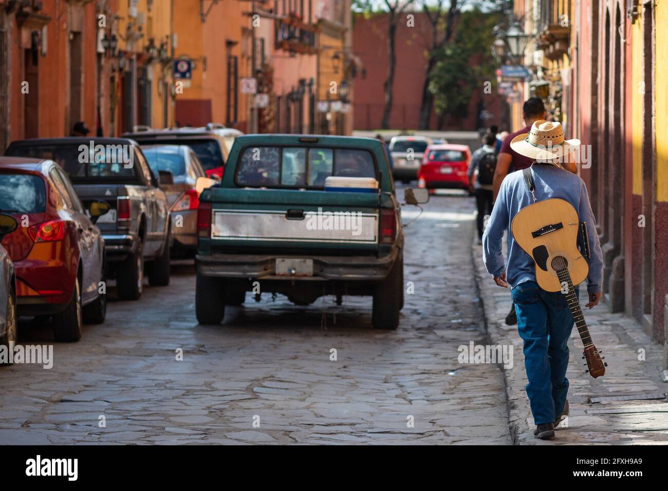 Street musician walking with his guitar on the streets of historical