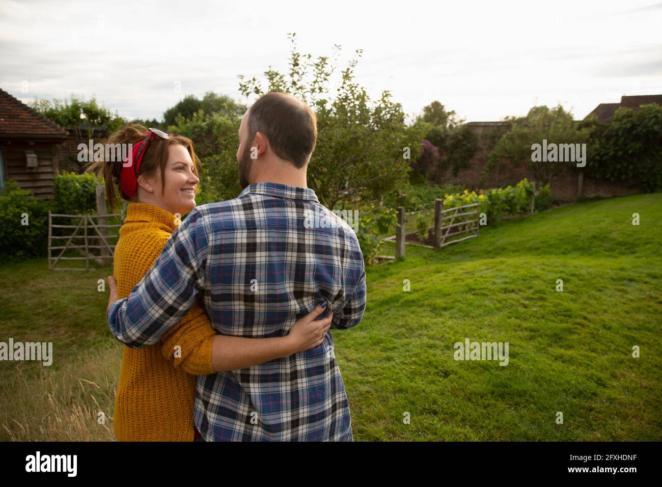 Happy affectionate couple hugging in idyllic cottage garden Stock Photo