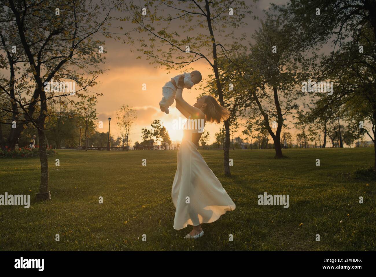 Happy harmonious family outdoors. mother throws baby up, laughing and