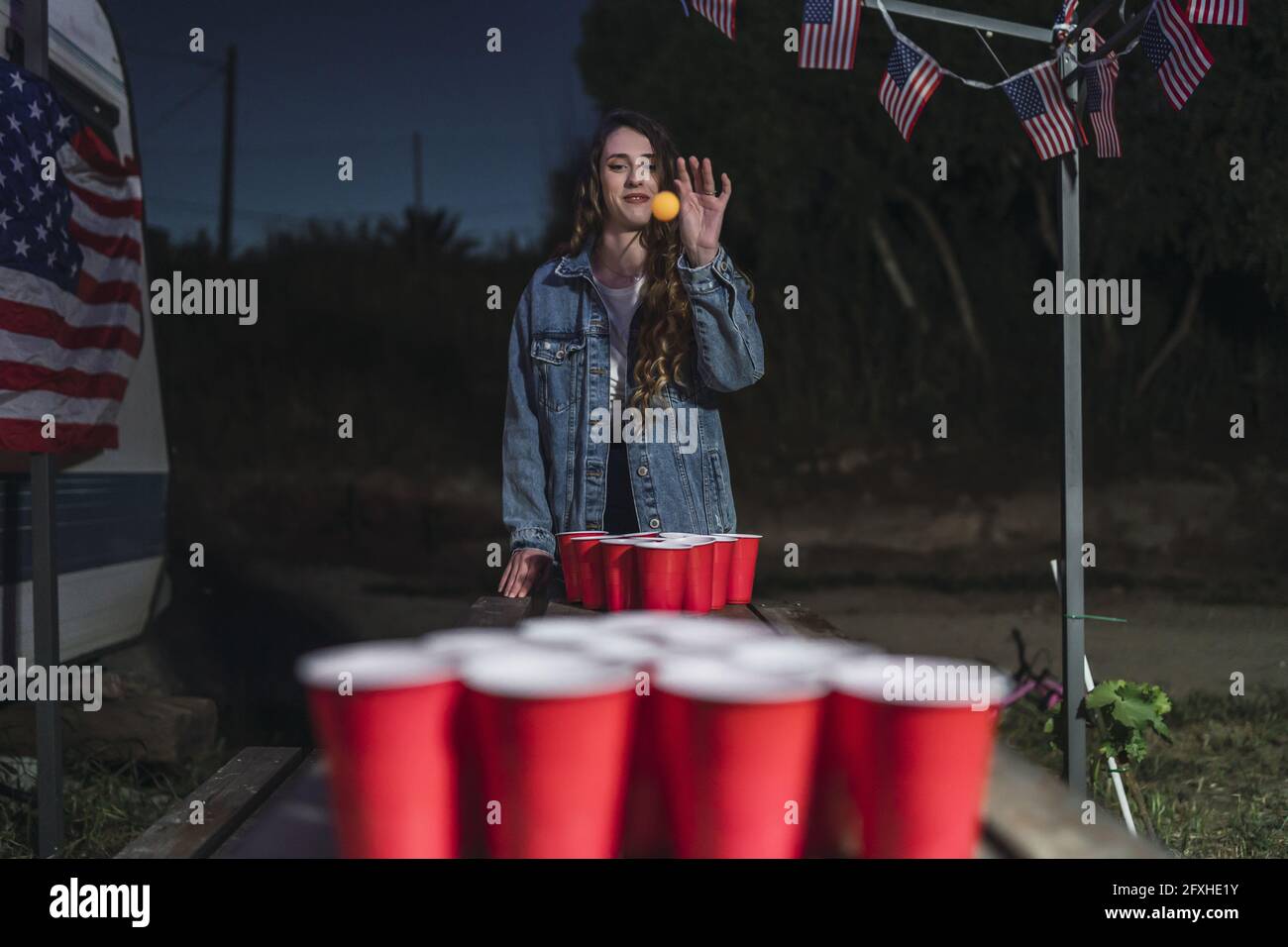Young Spanish female throwing the ball in beer pong cups outside at