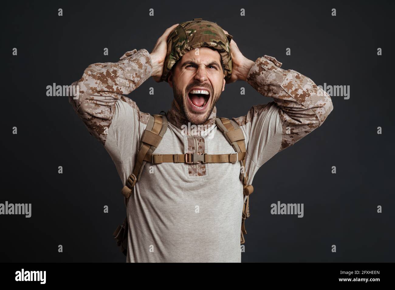 Furious military man in helmet screaming and grabbing his head isolated ...