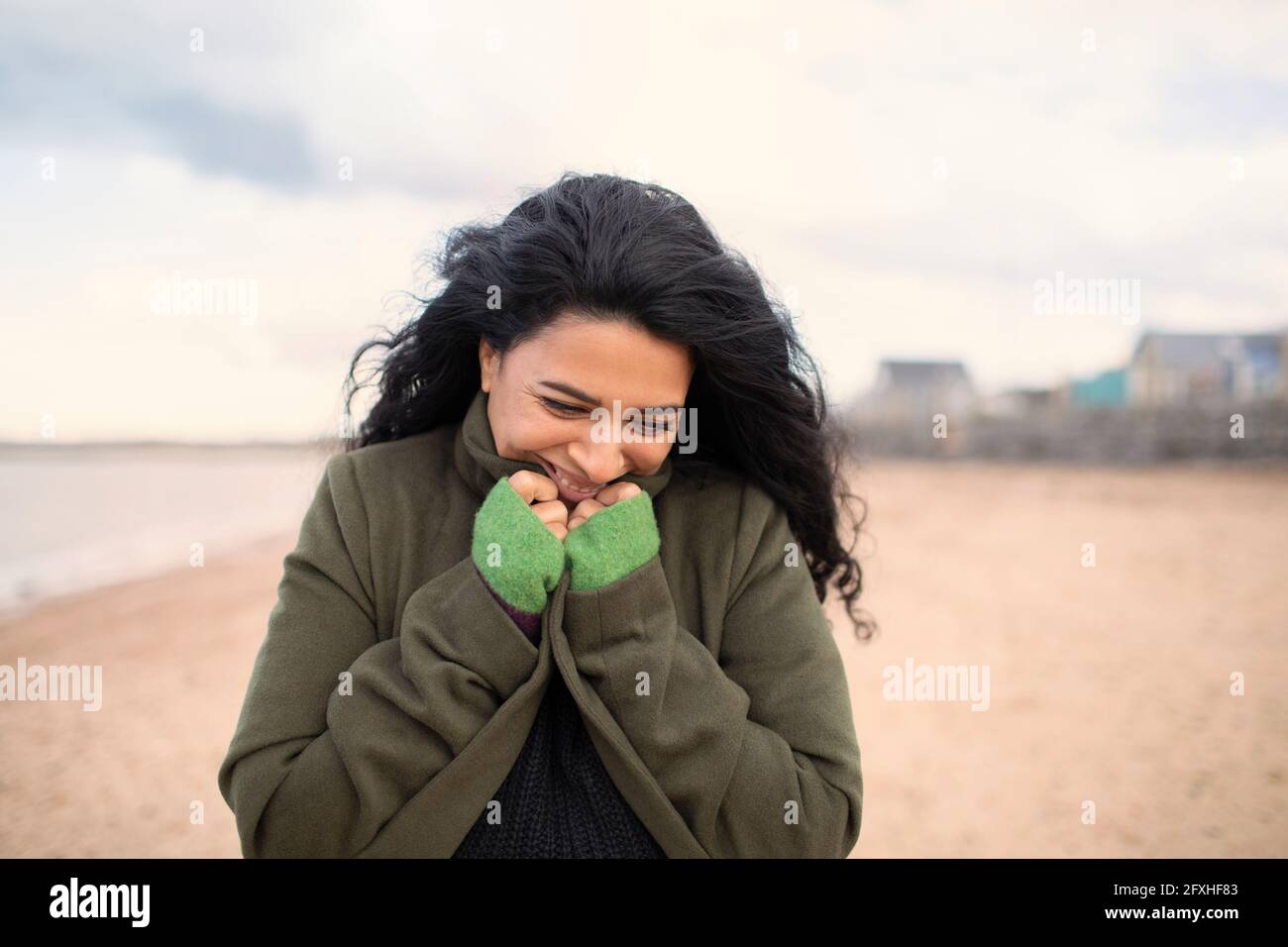 Happy woman in winter coat on beach Stock Photo