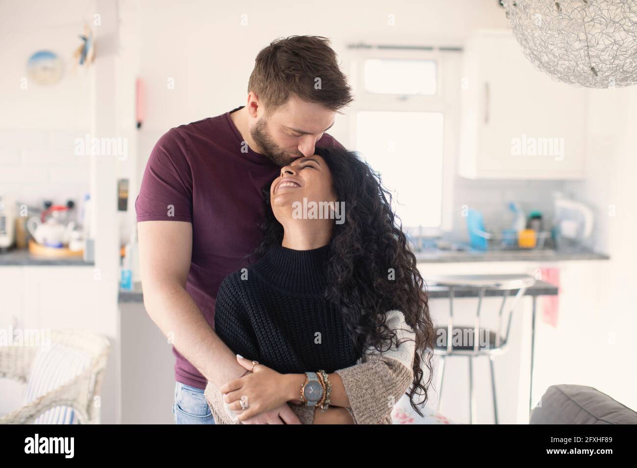 Happy affectionate couple hugging and kissing in kitchen Stock Photo