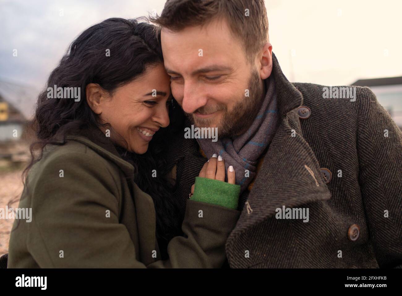 Happy affectionate couple in winter coats hugging Stock Photo