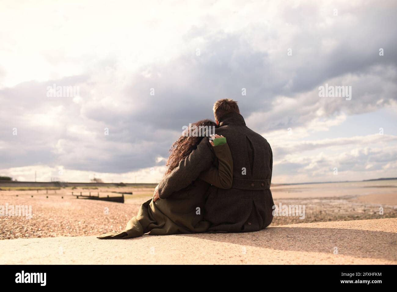 Serene affectionate couple hugging on sunny tranquil winter beach Stock Photo