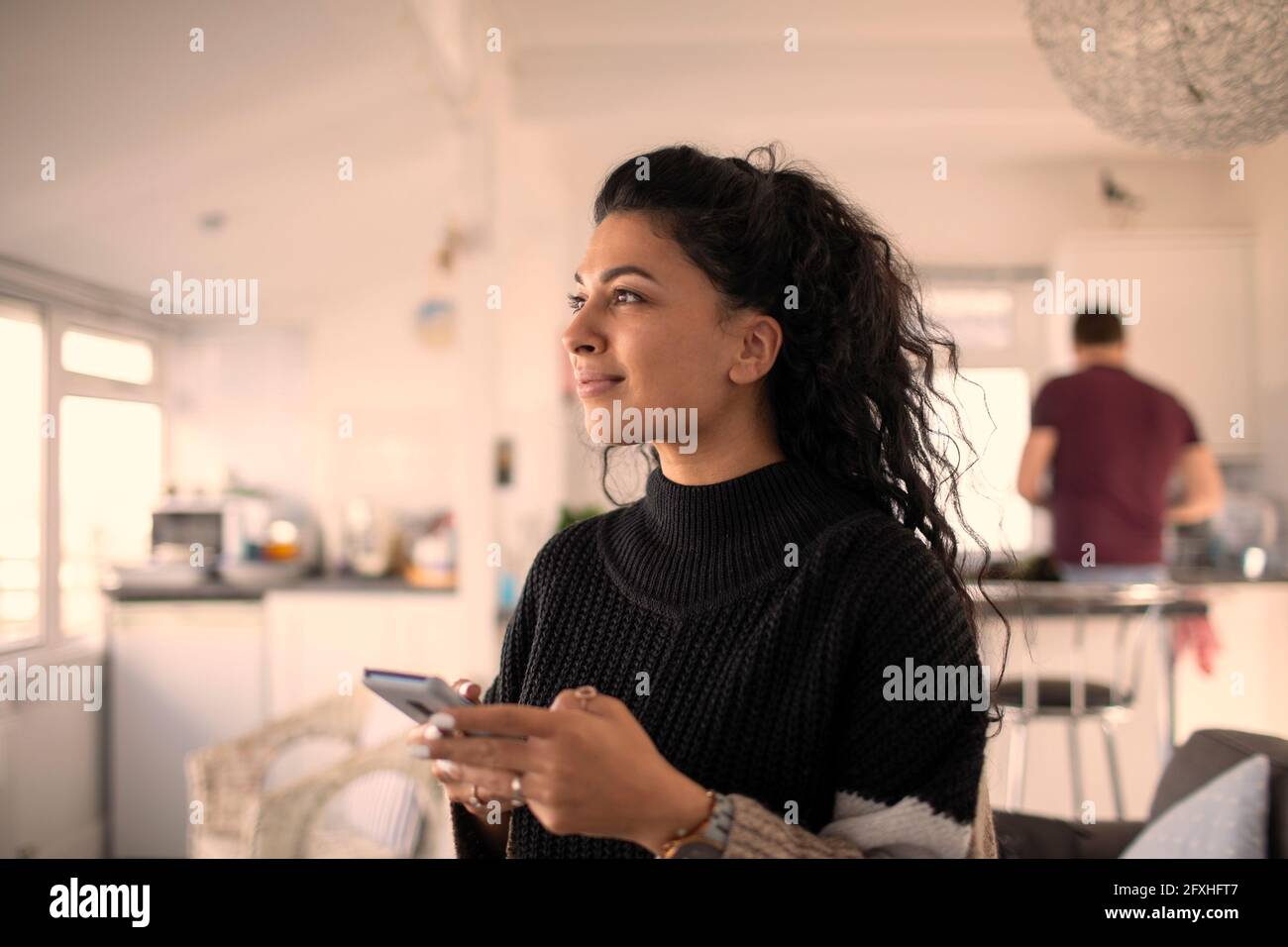 Smiling beautiful woman using smart phone at home Stock Photo