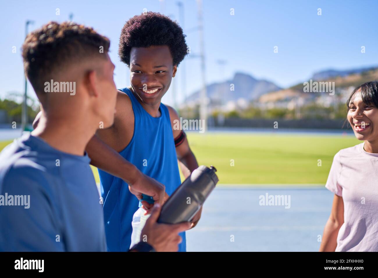 Happy young athletes talking on sunny sports track Stock Photo